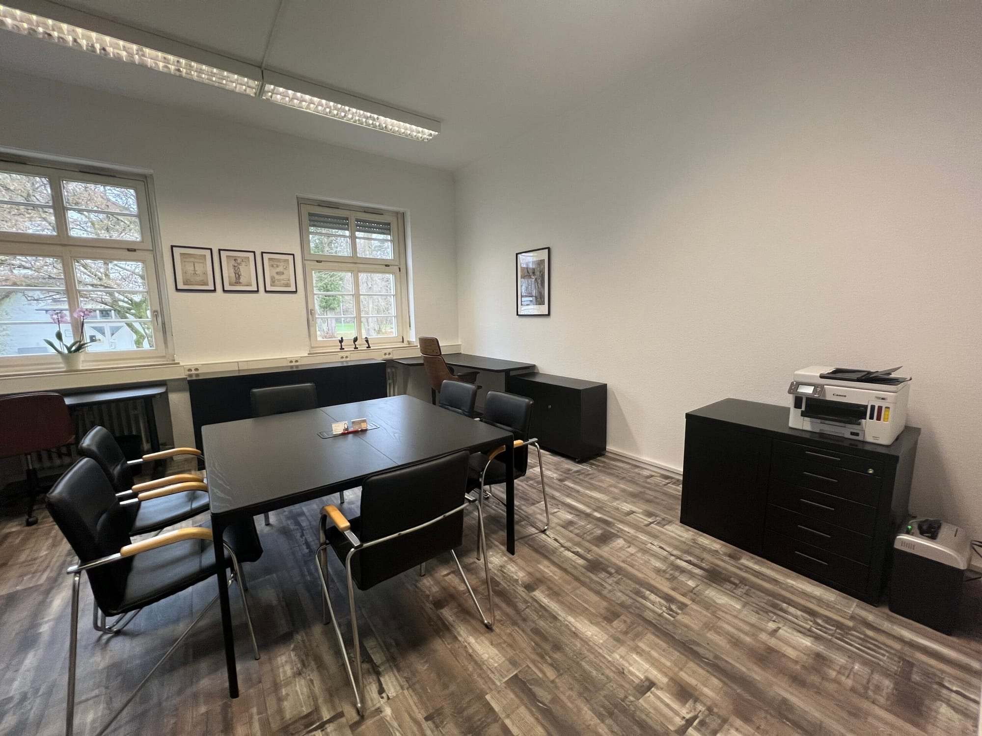 Konferans masası, pencere önünde çalışma alanı ve yazıcı bulunan toplantı odası